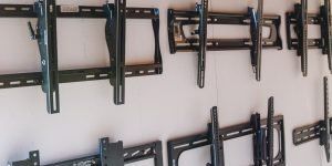 Several black TV mounts attached to a white wall.